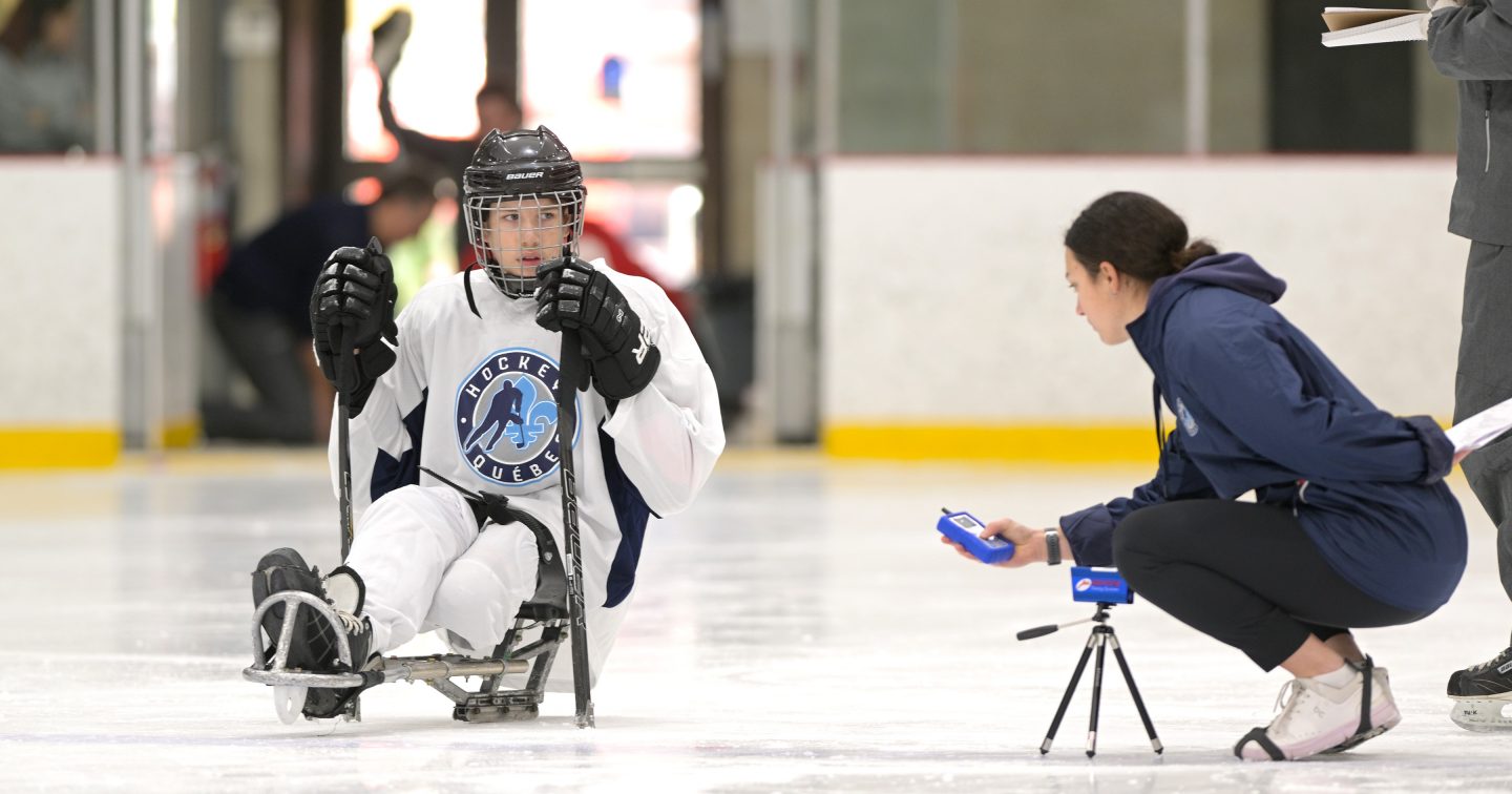 Thalia Krauth-Ibarz est accroupie avec un capteur, près d'un joueur de parahockey.