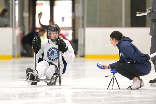 Thalia Krauth-Ibarz est accroupie avec un capteur, près d'un joueur de parahockey.