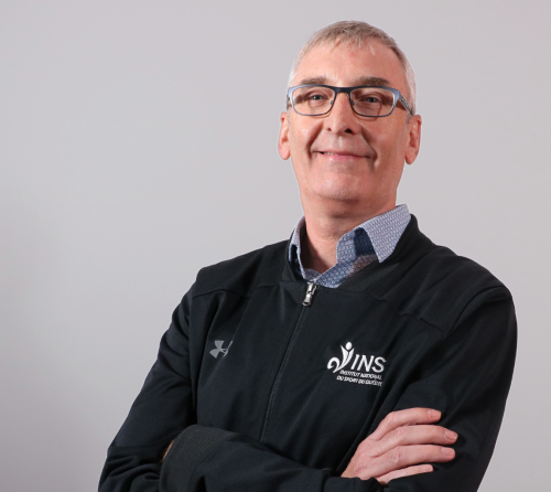 Photo de Marc Desjardins, souriant, les bras croisés.